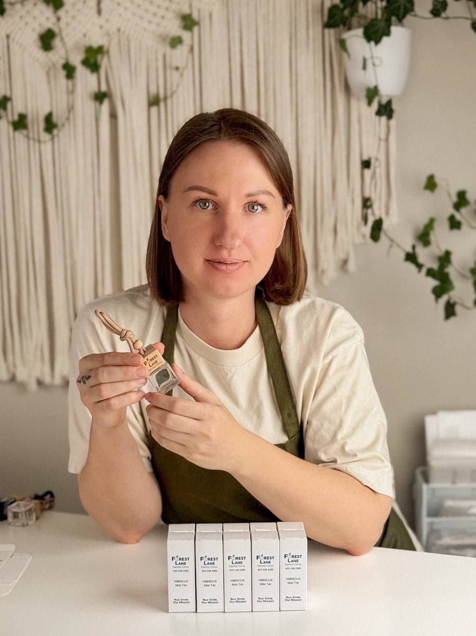 Anna holding a custom-branded car diffuser in the Calgary workshop